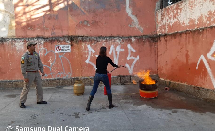 Instrução prática de Combate à Incêndios, brigadista executando o combate à incêndio com extintor de pó químico seco.